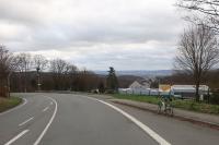 Ein Rennrad am Straßenrand, dahinter erstreckt sich ein weites Tal mit vielen Häusern.